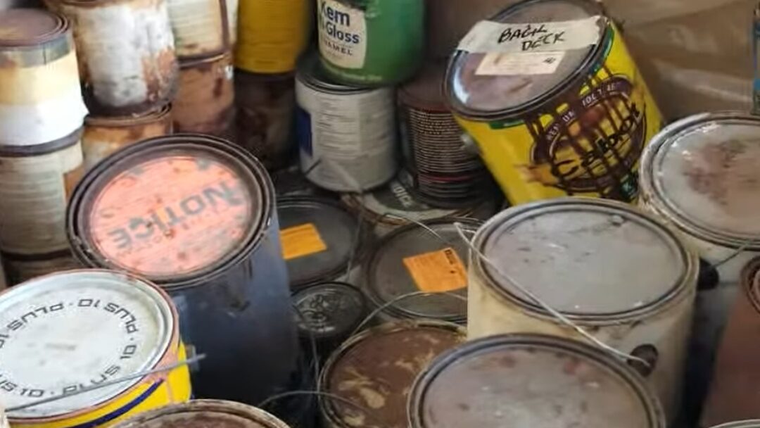 Assorted household hazardous waste containers, including paint cans and chemical products.