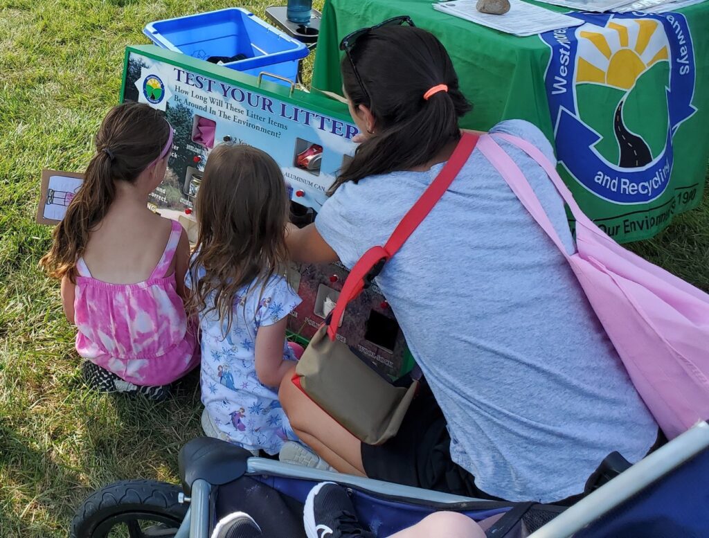 2 children and adult visiting the Cleanways' display table at an event