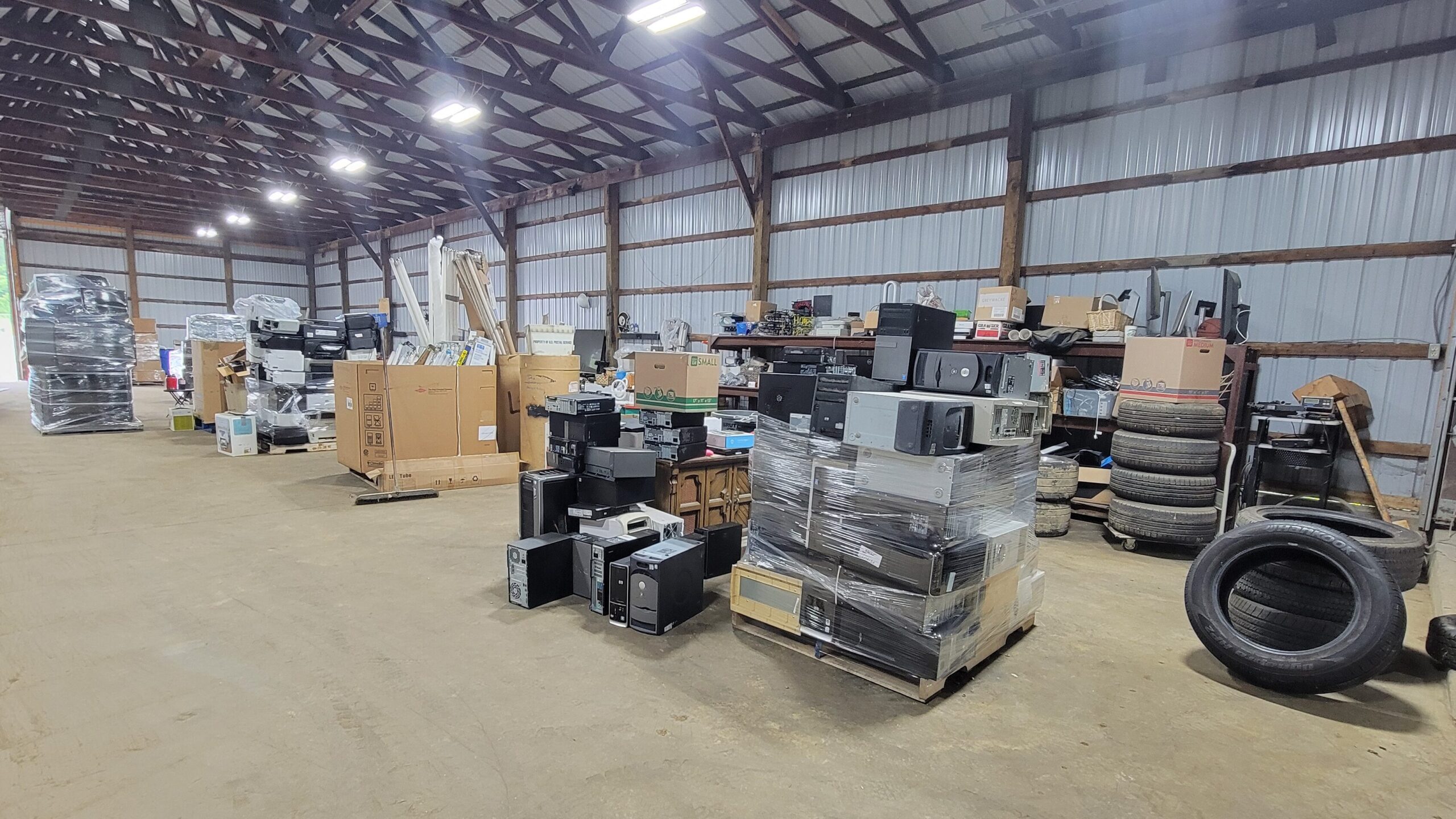 Interior of a recycling center with pallets of electronics, tires, and other recyclable materials.